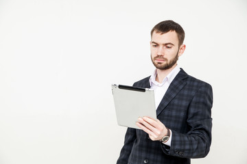 Portrait of a handsome young bearded man wearing a formal black suit holding a tablet