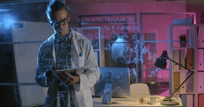 Student in walking in chemistry laboratory and using his tablet