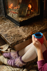 Fototapeta na wymiar Girl near siting the fireplace with a blue cup