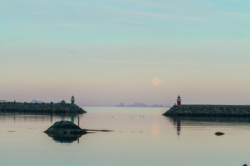 Two small lighthouses against mountain, full moon and twillight background