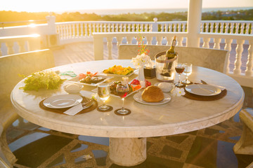 Table with food and drink for romantic dinner on sunset