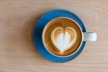 latte art served on blue cup and wooden background 