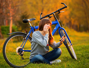 Fototapeta na wymiar Beautiful young woman using mobile phone sitting next to her bik