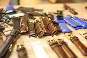 Many vintage watch straps on wood table for repair