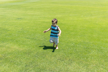Fototapeta premium Little kid running on green meadow