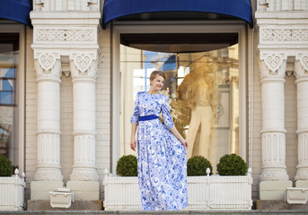 Fototapeta na wymiar Beautiful blonde girl in blue dress posing against a background