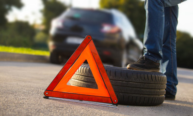 Sad and depressed man sitting near car with punctured tire