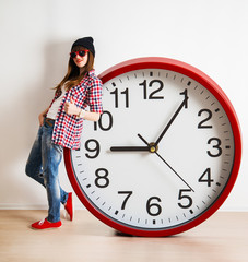 young woman with hat and glasses holding a clock. time management concept. nine o`clock