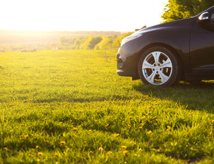 black car without a trade brand on grass at sunset