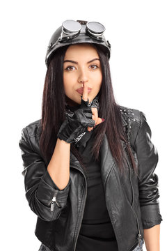 Female biker holding a finger on her lips