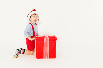 Happy caucasian Xmas toddler opening a big Christmas gift box - isolated on white background