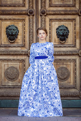 Obraz premium Beautiful blonde girl in blue dress posing against a background