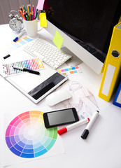 Modern office workplace with digital tablet, notepad, colorful p