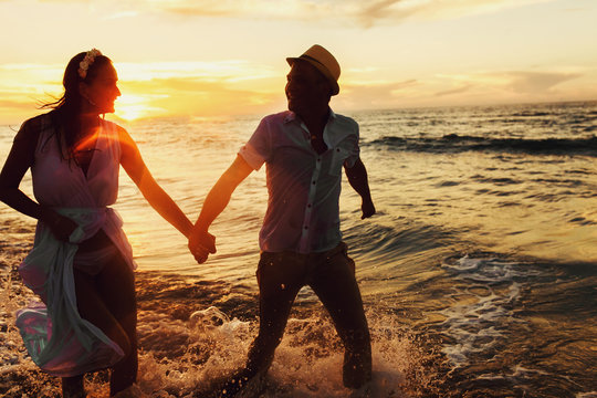 beautiful sunset in the ocean and happy couple holding hands