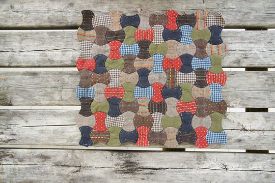 Patchwork/quilt Applecore Quilt In Red, Khaki, Blue And Lightbrown With The Old Wood Background