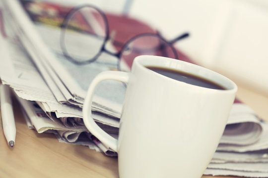 Cup of coffee and newspaper on table