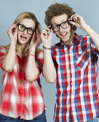  Portrait of gorgeous blond fashion man and woman in casual shirt, wearing trendy glasses posing on blue background. Perfect skin and hairdo. Vogue style. Close up. Studio shot. 