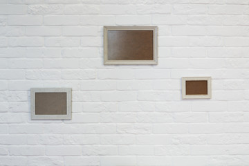 Naklejka na ściany i meble Empty picture frame at white brick wall