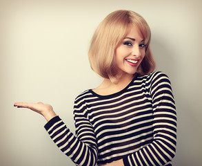 Beautiful makeup blond woman holding and presenting something in