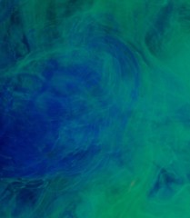 Fototapeta na wymiar Blue green clouds of ink in liquid