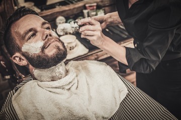 Client during beard shaving in barber shop