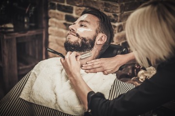 Client during beard shaving in barber shop