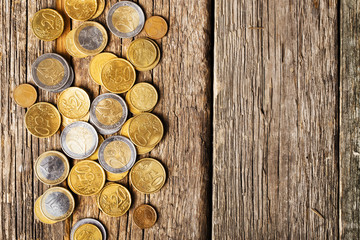 Top view coins on old wooden desk with copy space on top.