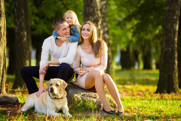 Obraz premium Happy family with their dog in the park on a sunny day
