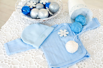 Obraz na płótnie Canvas Anticipation. Blue baby clothes on lace beckground with Christmas balls and knitting balls