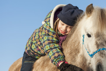 Little girl with horse outdoor in winter