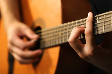 Young musician playing acoustic guitar close up