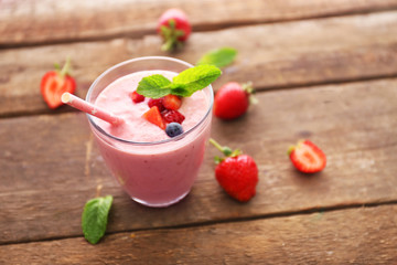 Fresh strawberry yogurt with berries around on wooden background