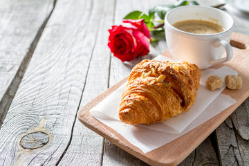 Delicious fresh croissants with coffee and rose