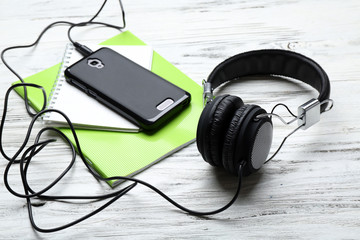 Headphones with notebooks and smartphone on wooden table