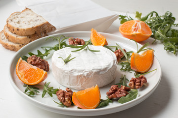 Camembert.Camembert cheese on the plate with fruits and nuts.