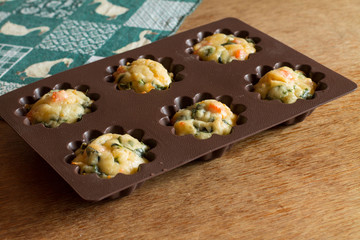 Muffin with salmon, spinach and cheese in silicone bakeware on green tablecloth with gooses.