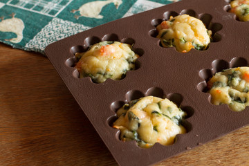 Muffin with salmon, spinach and cheese in silicone bakeware on green tablecloth with gooses.
