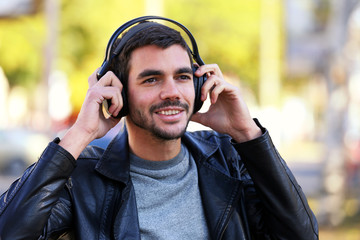 Young man listening to music and walking along the street