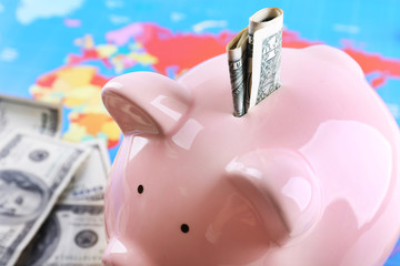 Money box pig on world map background