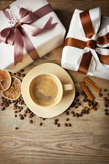 Beautiful gift, cup with coffee and coffee grains on wooden background