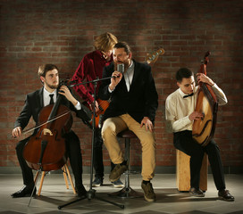 Fototapeta premium Man's musical band on brick wall background in the studio