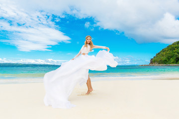 Fototapeta na wymiar Beautiful blond bride in white wedding dress with big long train