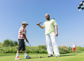 Father teaching son playing golf at club