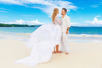 Fototapeta na wymiar Happy bride and groom having fun on a tropical beach. Wedding an