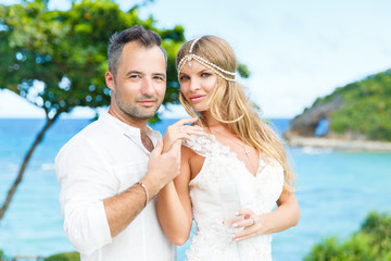 Happy bride and groom having fun on a tropical beach. Wedding an