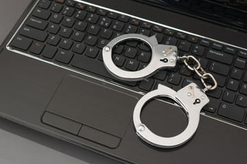 Handcuffs on a laptop keyboard. Concept photo for online fraud
