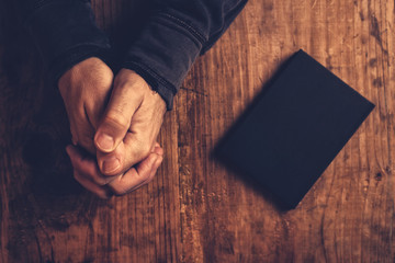 Christian man praying with hands crossed
