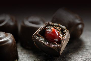 chocolate pralines with red fruit filling on a dark rustic woode