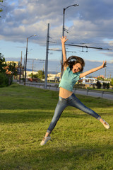 Surprised girl jumps high next to a road outside .