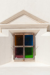 Closeup of Small and Colorful red green blue orange glass Window in stone